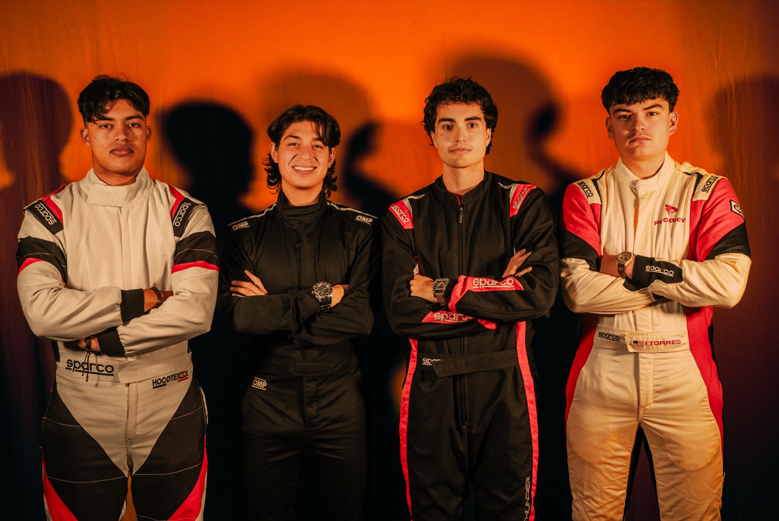 Four Gold Trail Racing team members in race suits, arms crossed