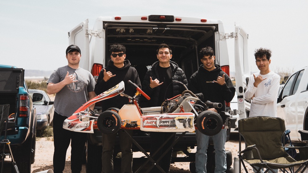 Five team members with a kart in front of the team van